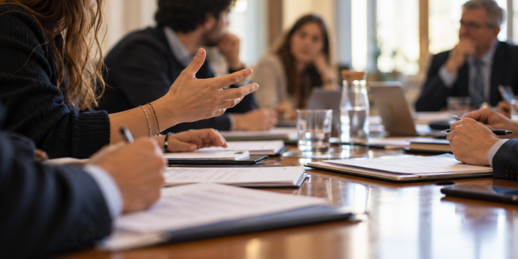 Docenti e giovani rappresentanti si confrontano intorno a un tavolo in una sala riunioni universitaria.