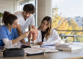 Tre laureati delle professioni sanitarie studiano insieme in un’aula universitaria