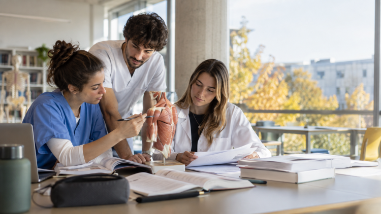 Tre laureati delle professioni sanitarie studiano insieme in un’aula universitaria