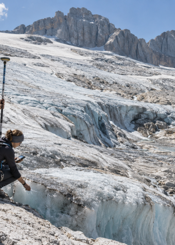 Ricercatori universitari misurano il ritiro di un ghiacciaio alpino tra ghiaccio e rocce esposte.