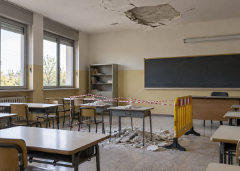 Aula scolastica con intonaco caduto dal soffitto e area transennata per motivi di sicurezza.