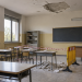 Aula scolastica con intonaco caduto dal soffitto e area transennata per motivi di sicurezza.