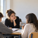 Una docente segue due studenti durante un’attività di apprendimento dell’italiano