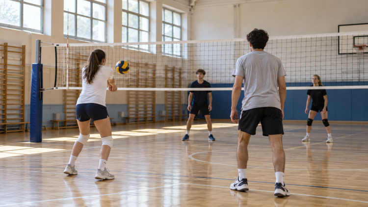 Studenti di spalle durante un’attività di pallavolo in una palestra scolastica.