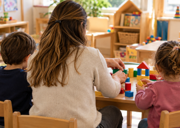 Insegnante e bambini svolgono un’attività con costruzioni nella scuola dell’infanzia.