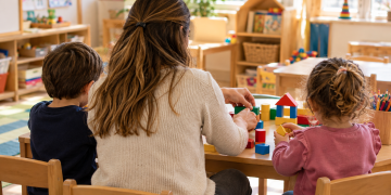 Insegnante e bambini svolgono un’attività con costruzioni nella scuola dell’infanzia.