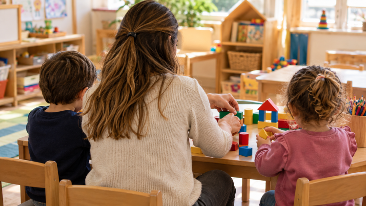 Insegnante e bambini svolgono un’attività con costruzioni nella scuola dell’infanzia.