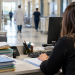 Addetta amministrativa vista di spalle al computer in un ufficio ospedaliero.