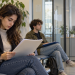 Due giovani con documenti in mano attendono un colloquio di lavoro in una sala d’attesa.