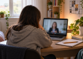 Studentessa ripresa di spalle davanti a un computer durante un colloquio psicologico online.
