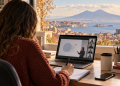 Studentessa segue una lezione online al computer con il golfo di Napoli sullo sfondo.